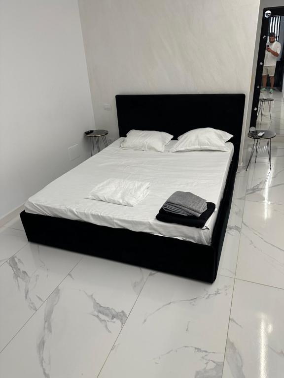 a bed with a black frame and white sheets and pillows at Garsoniera Zona Stadion in Craiova
