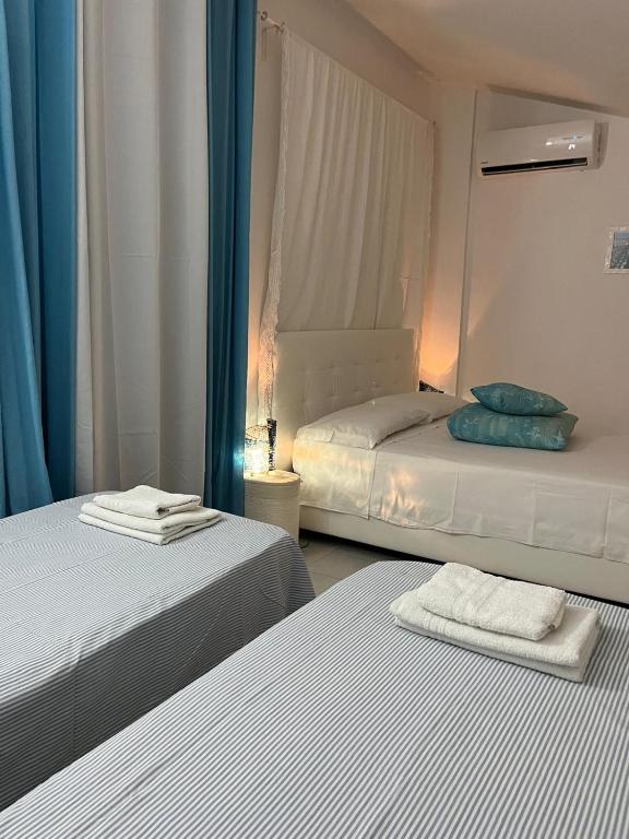 two beds in a room with blue curtains at B&B Villa Mediterranea with private parking in Trani