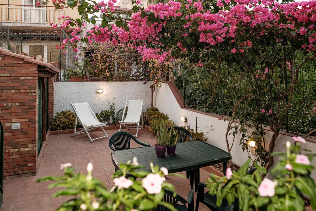 a patio with a table and chairs and pink flowers at La campagna e il mare in Catania