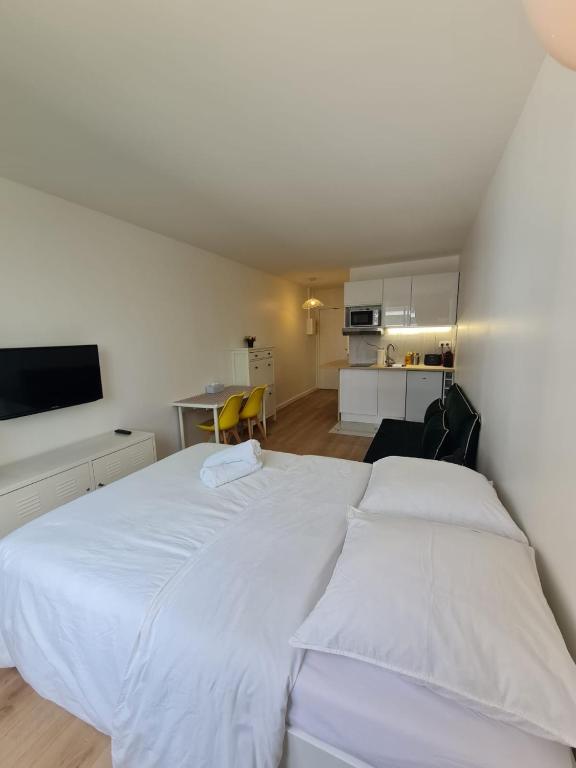 une chambre avec un grand lit blanc et une cuisine dans l'établissement Super studio Paris La Défense, à Courbevoie