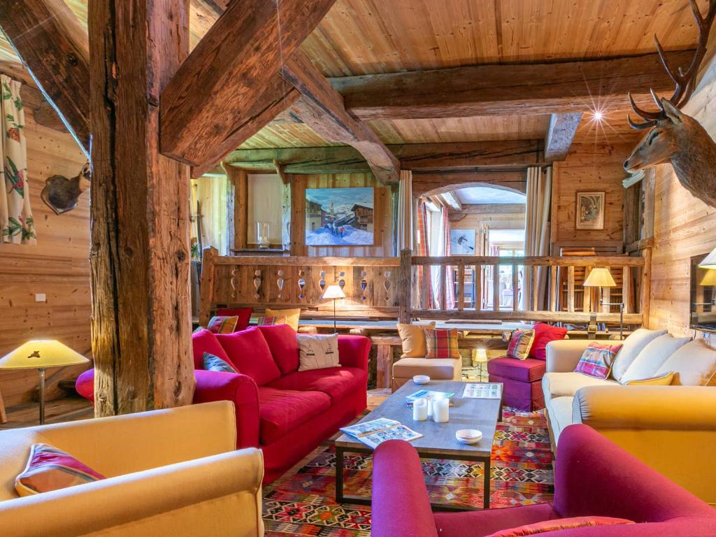 un salon avec des meubles rouges et une tête de cerf sur le mur dans l'établissement Superbe appartement chalet, plein sud, au pied des pistes avec services haut de gamme - FR-1-694-356, à Val dʼIsère