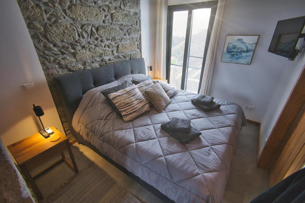 una camera da letto con un letto con un muro di pietra di Coração da Quinta ad Algarvia