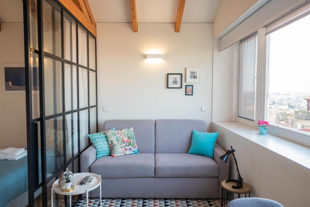 een woonkamer met een bank en een raam bij Panoramic luxury apartment w AC Downtown and Metro in Porto