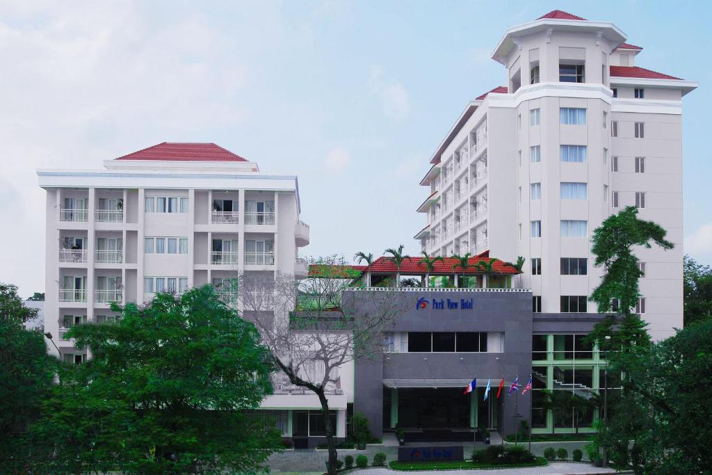 two tall white buildings with trees in front of them at Park View Hotel in Hue