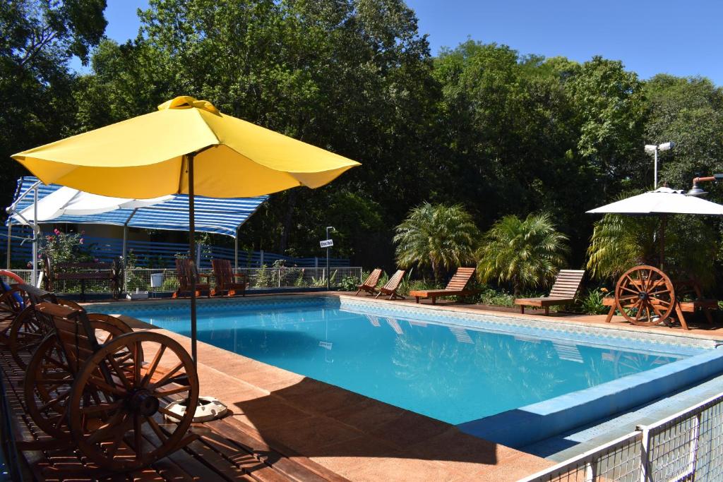 una piscina con ombrellone e sedie gialli di Cabañas Oberá a Oberá