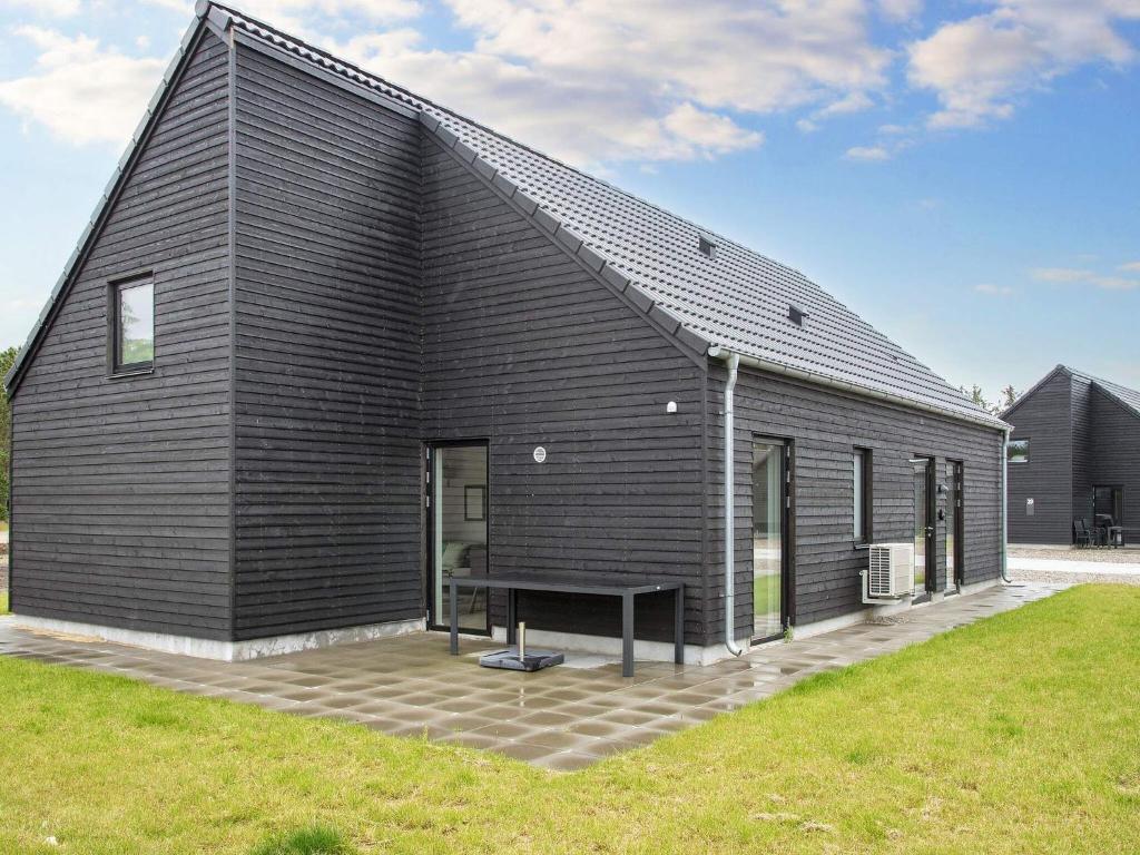 a black house with a bench in front of it at 8 person holiday home in Rømø in Kongsmark