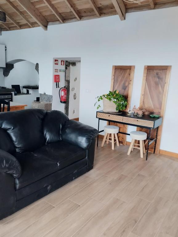 a black leather couch in a living room with a piano at Casa da Tia Avelina in Angra do Heroísmo
