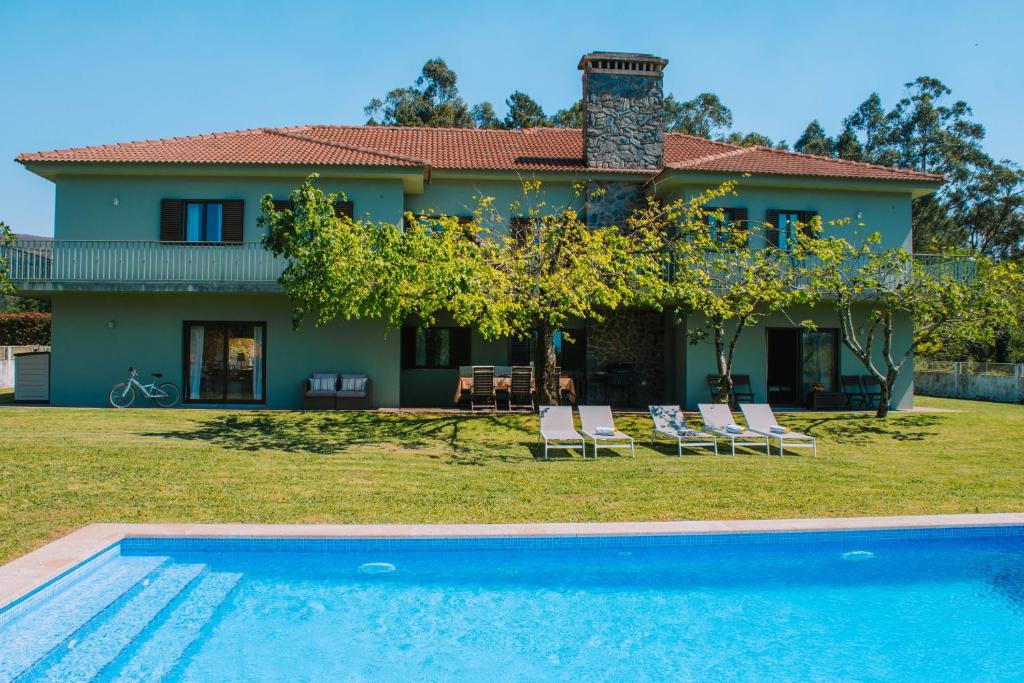 a villa with a swimming pool in front of a house at Just Like Home - Casa de Cimo de Vila in Vila Nova de Cerveira
