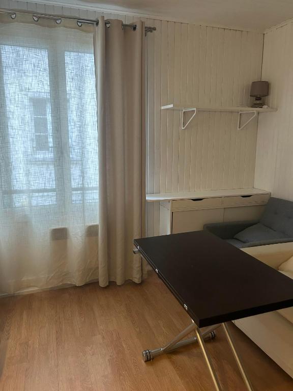 un salon avec une table et une fenêtre dans l'établissement Idéal, à Vincennes