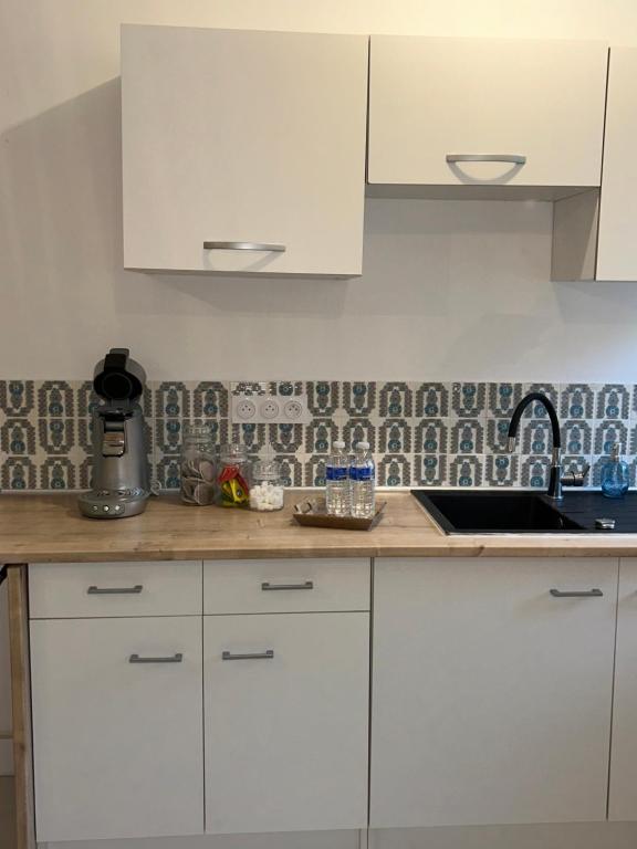 une cuisine avec des armoires blanches et un comptoir dans l'établissement Spacieux T2 climatisé - Près du centre ville, à Narbonne