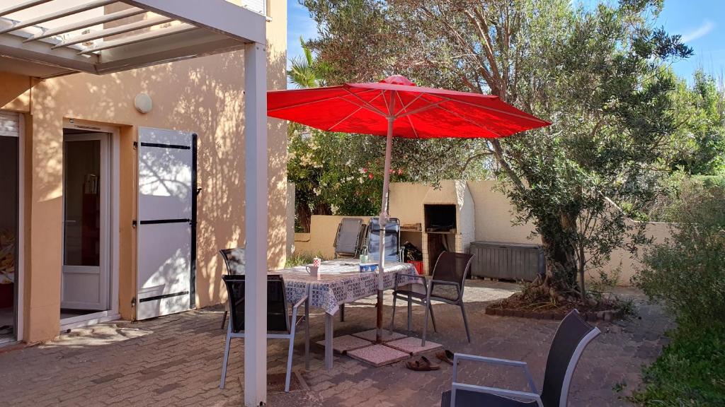 - une table avec un parasol rouge sur la terrasse dans l'établissement Appartement avec vaste terrasse à 30 m des dunes, au Cap d'Agde
