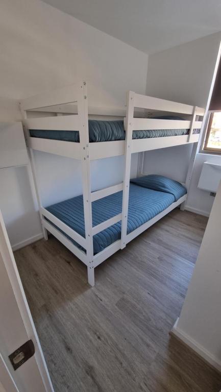 Ce lit se trouve dans un dortoir doté de 2 lits superposés blancs et de parquet. dans l'établissement Departamento 2H 1B en Punta Puyai, à Papudo