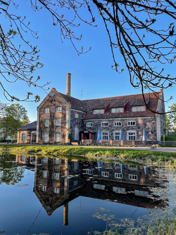 an old building with its reflection in a body of water at Utoopia Külalistemaja Viscosas in Kõrgessaare