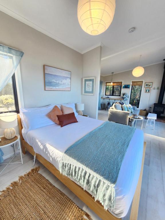 a bedroom with a large bed and a living room at Flotsam Seaside Studio Dunalley in Dunalley