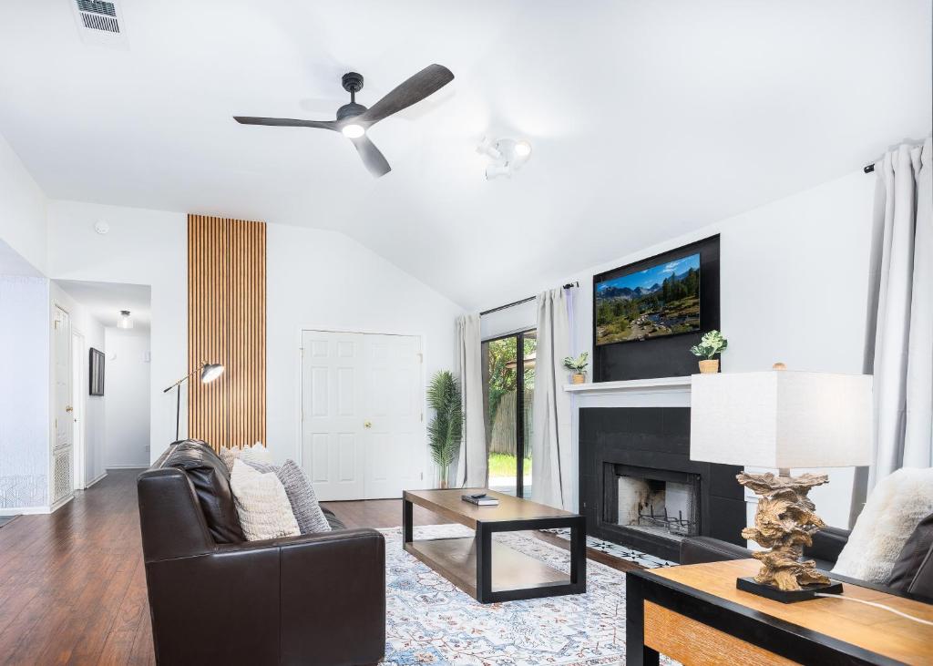 a living room with a ceiling fan and a fireplace at Cozy, Round Rock Retreat, Modern, Sleeps 10 in Round Rock