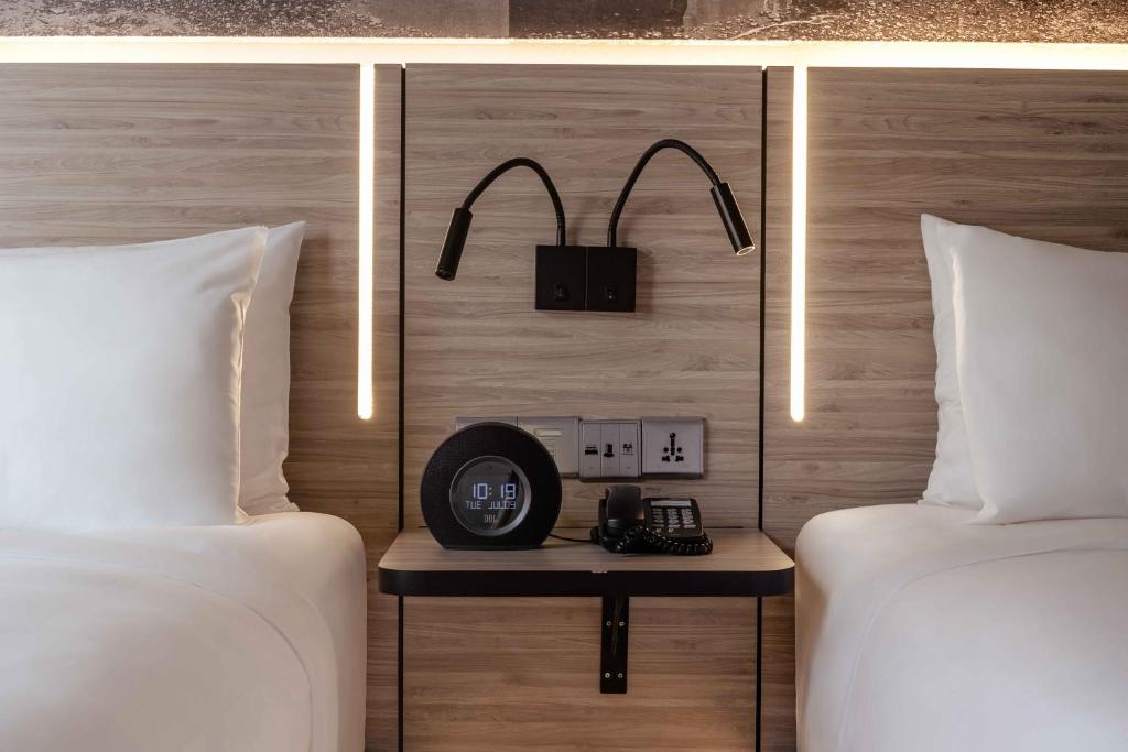 a room with two beds and a clock on a table between them at The Kuala Lumpur Journal Hotel in Kuala Lumpur