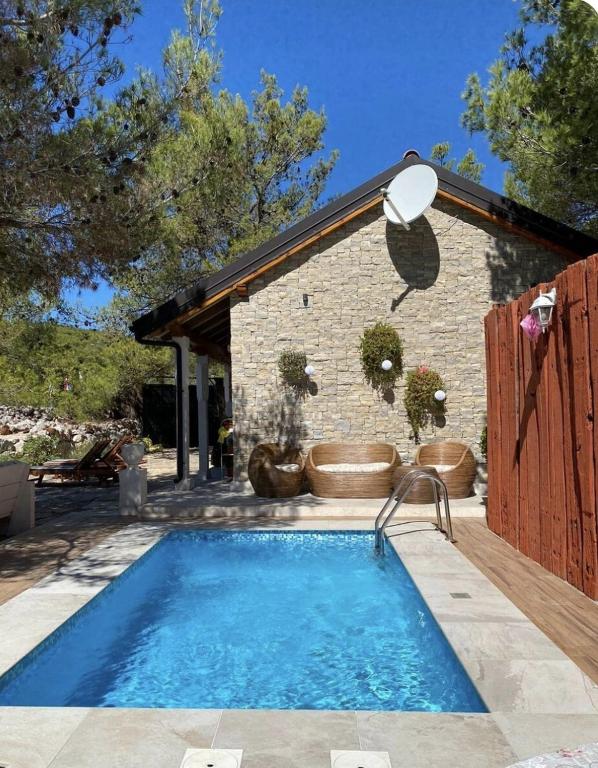 a swimming pool in front of a brick building at Kuća za odmor Brigitaa in Jezera