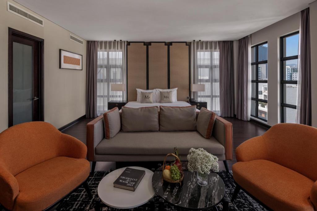 An open-plan suite with a bed behind a sofa and a lounge area facing the windows.