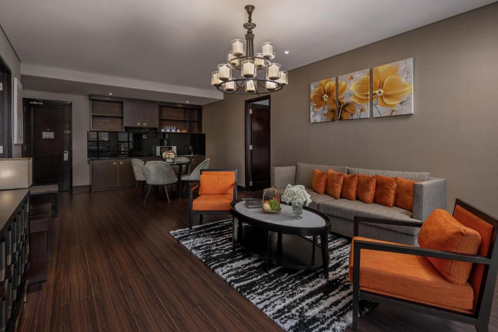 A formal suite lounge with orange armchairs, a gray sofa, dining seating, and a kitchenette-style cabinet.