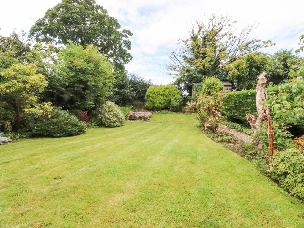 a yard with a large lawn with trees and bushes at Stork Cottage in Lancaster
