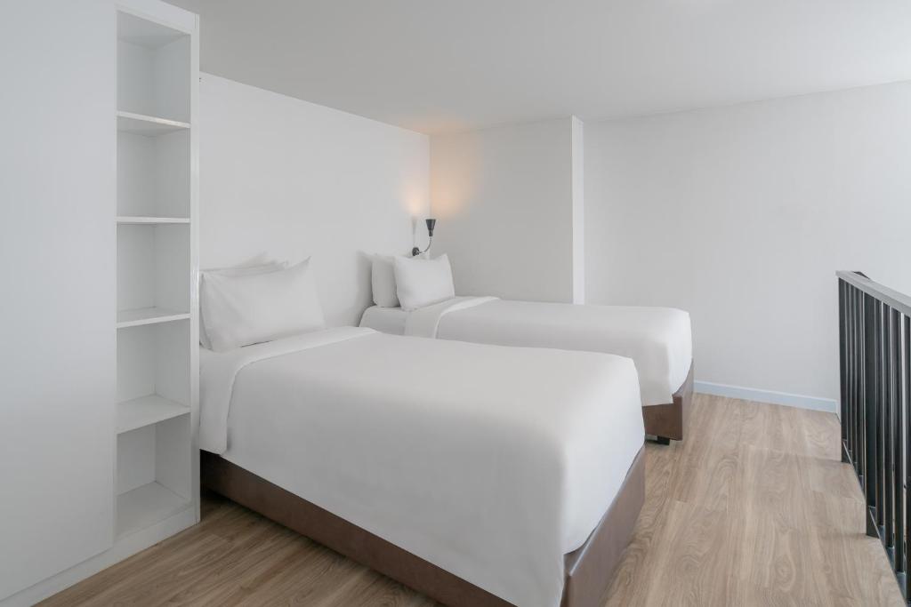 A bright twin room with two beds and pale wood flooring.