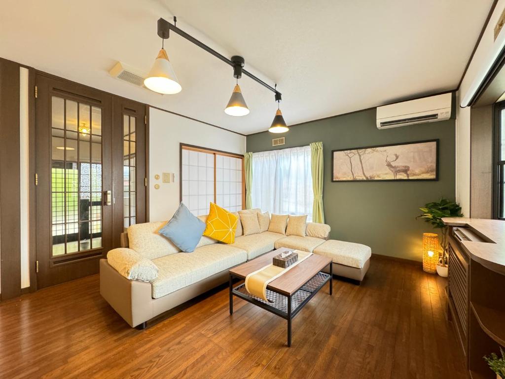 een woonkamer met een bank en een tafel bij New OPEN BBQ ウッドデッキ テントサウナ 最大13名宿泊可能 in Yamanakako