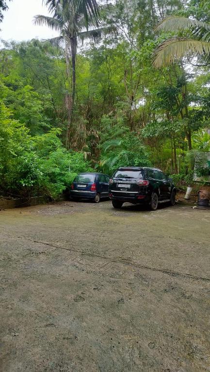 two cars parked in a parking lot next to trees at Kalapani Nest in Port Blair