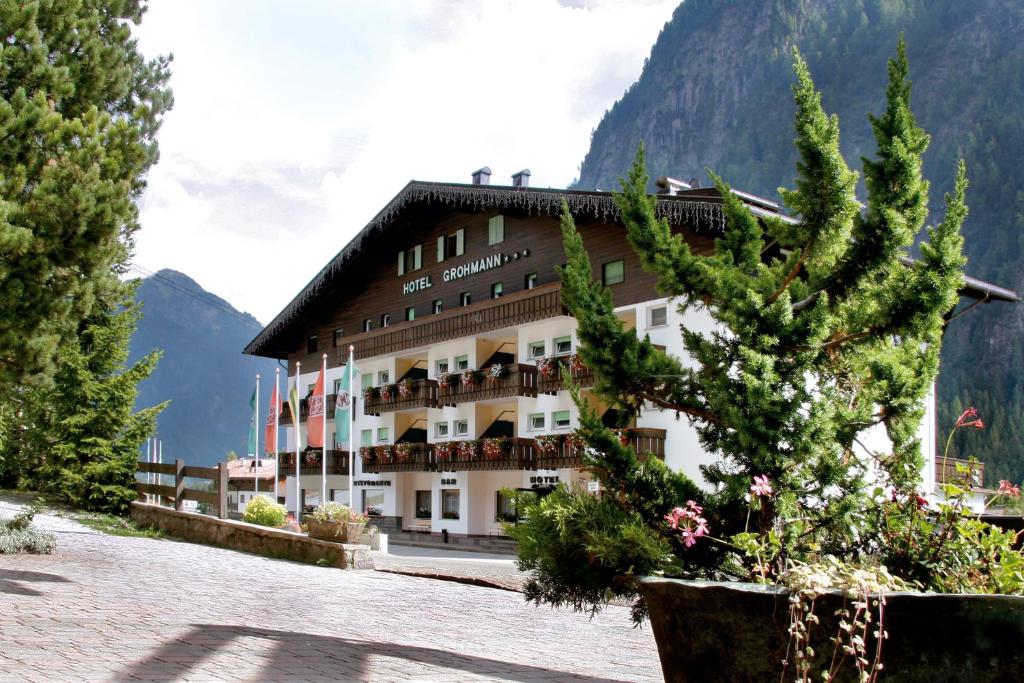 duży budynek z drzewem przed nim w obiekcie Hotel Grohmann w mieście Campitello di Fassa