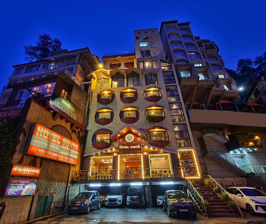 a tall building with cars parked in front of it at Hotel Surya Shimla in Shimla