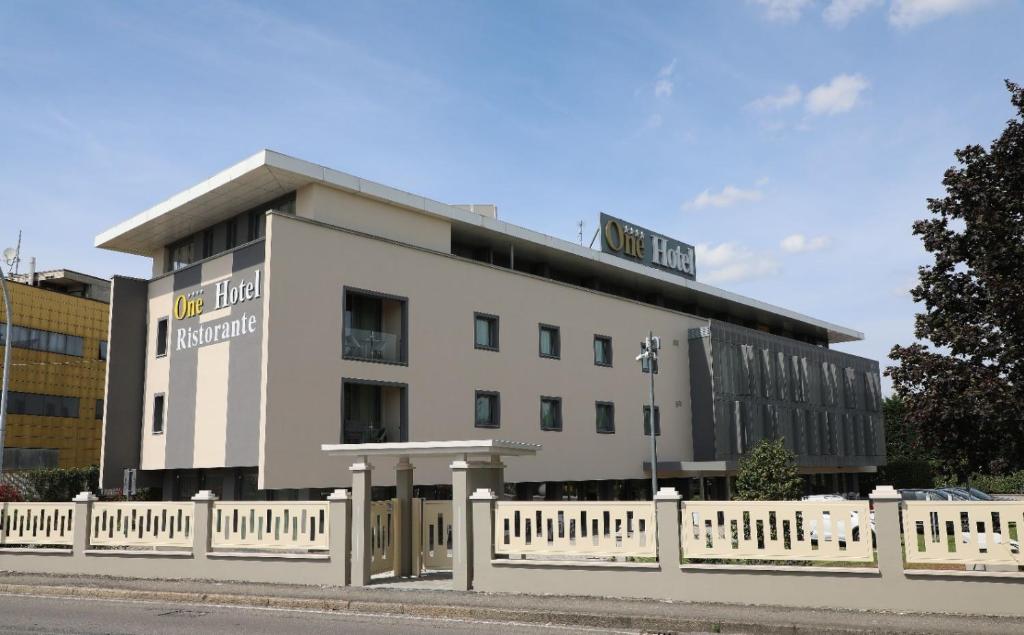 a white building with a fence in front of it at One Hotel & Restaurant in Dalmine