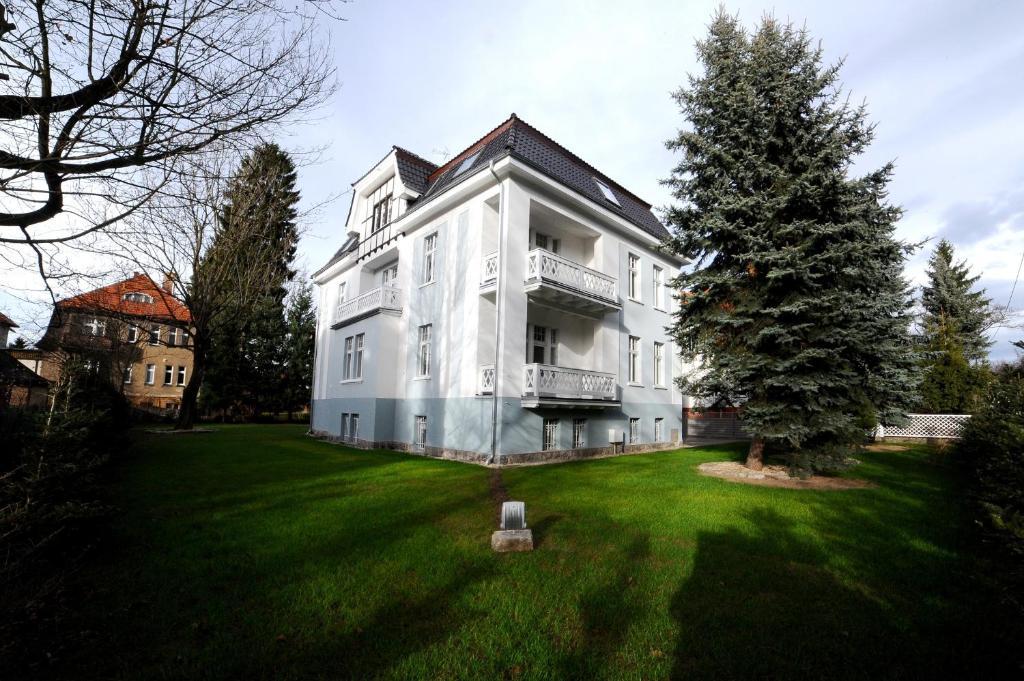 uma grande casa branca com uma árvore no quintal em Villa Cervi em Jelenia Góra