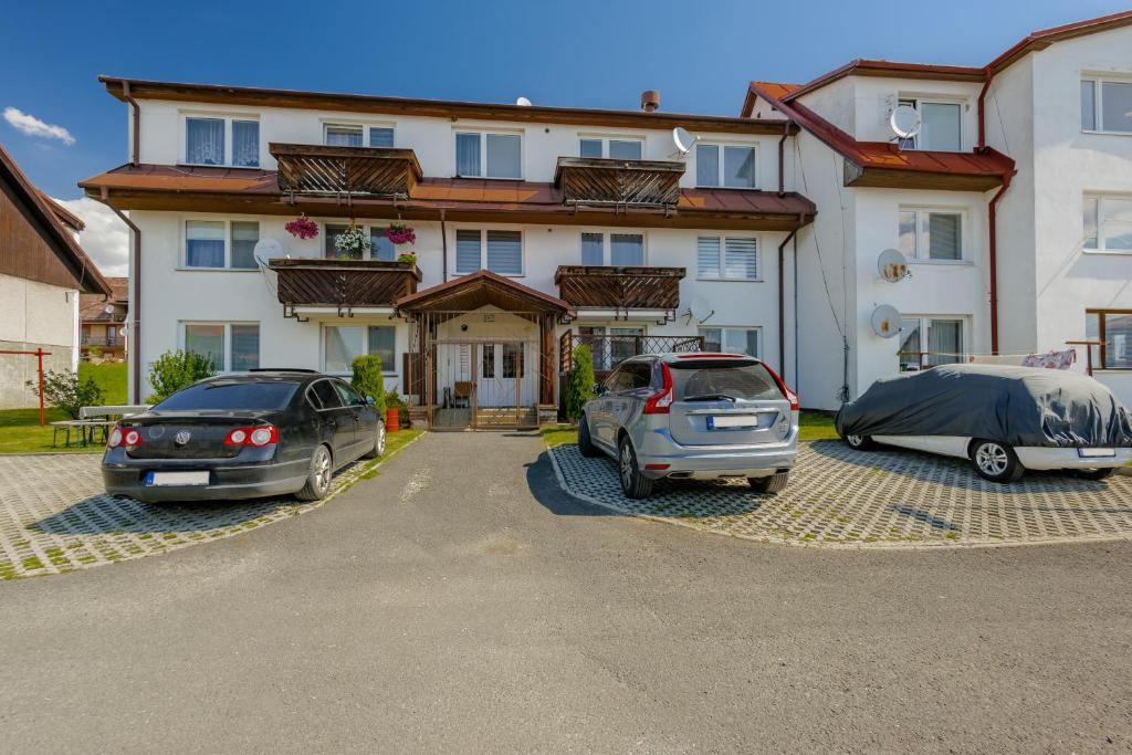 two cars parked in a parking lot in front of a house at Apartmán Tatry Lesná in Nová Lesná
