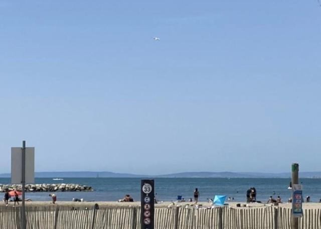 Une plage avec une clôture et des gens sur elle dans l'établissement Les pieds dans le sable, au Grau-du-Roi