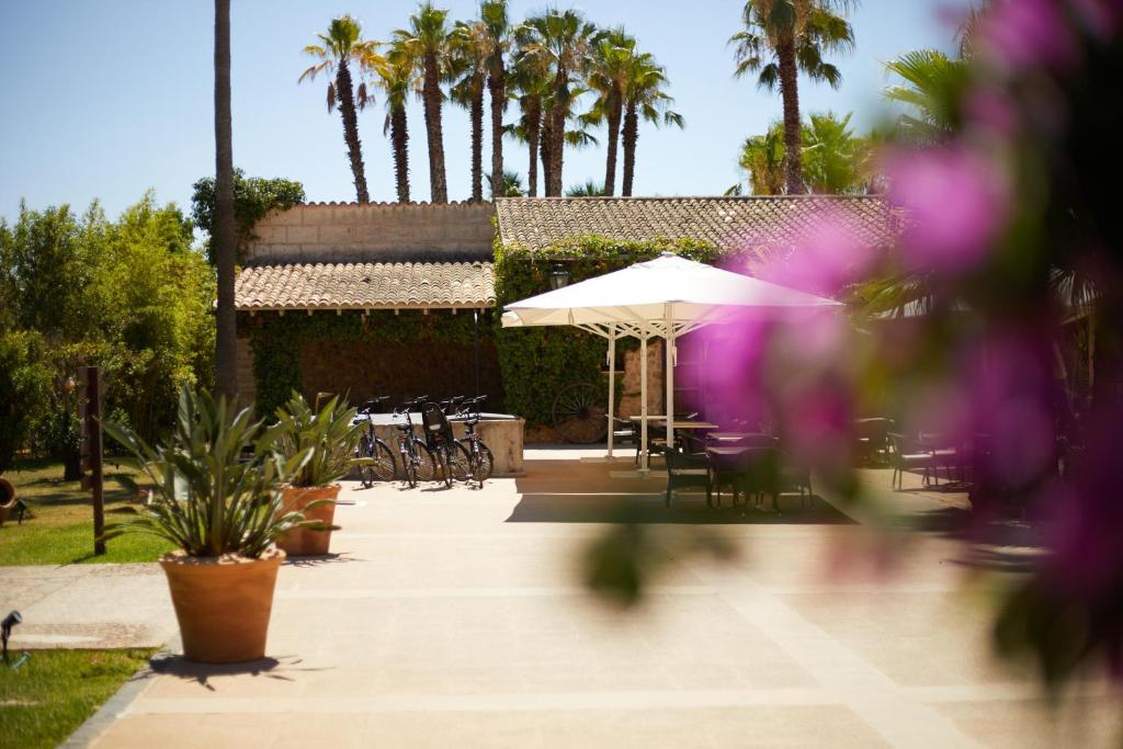 a patio with tables and chairs and an umbrella at Virrey Finca Hotel in Inca