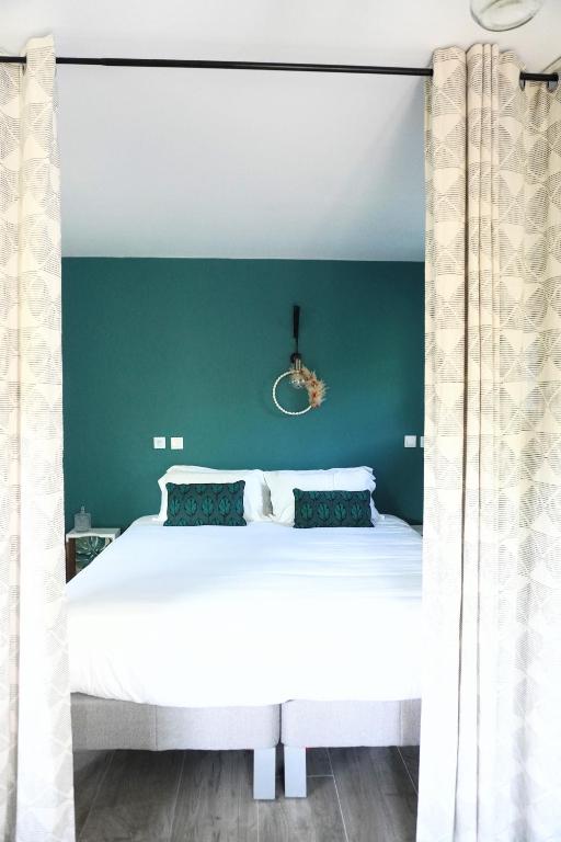 une chambre avec un lit blanc avec un mur vert dans l'établissement La Quintita Biarritz - studio avec jardin, à Biarritz