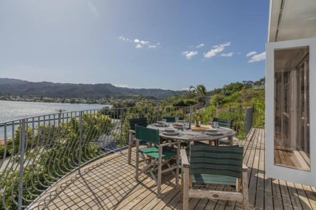 eine Terrasse mit Tisch und Stühlen auf einem Balkon in der Unterkunft The Harbour Masters Cottage in Tairua
