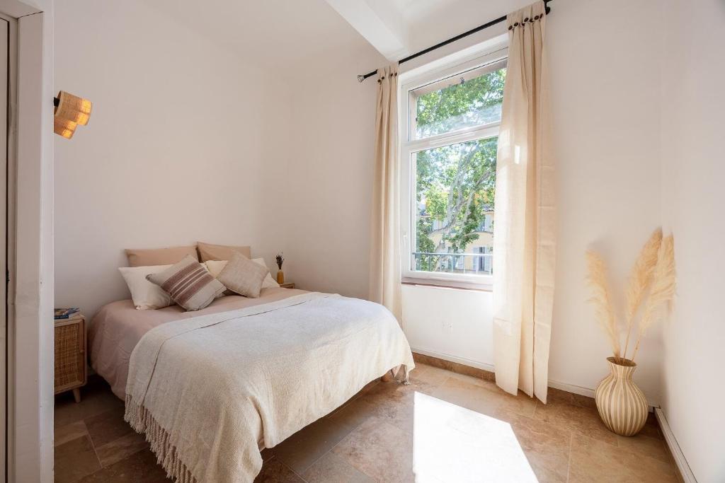 une chambre blanche avec un lit et une fenêtre dans l'établissement La Suite Provençale, à Aix-en-Provence