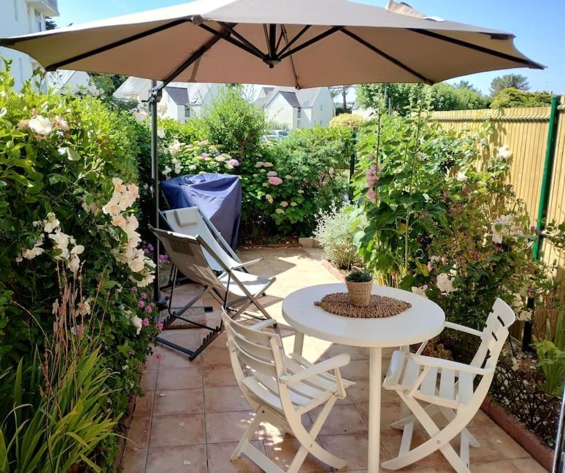 ein Tisch und Stühle unter einem Sonnenschirm auf einer Terrasse in der Unterkunft Appartement avec terrasse in Quiberon