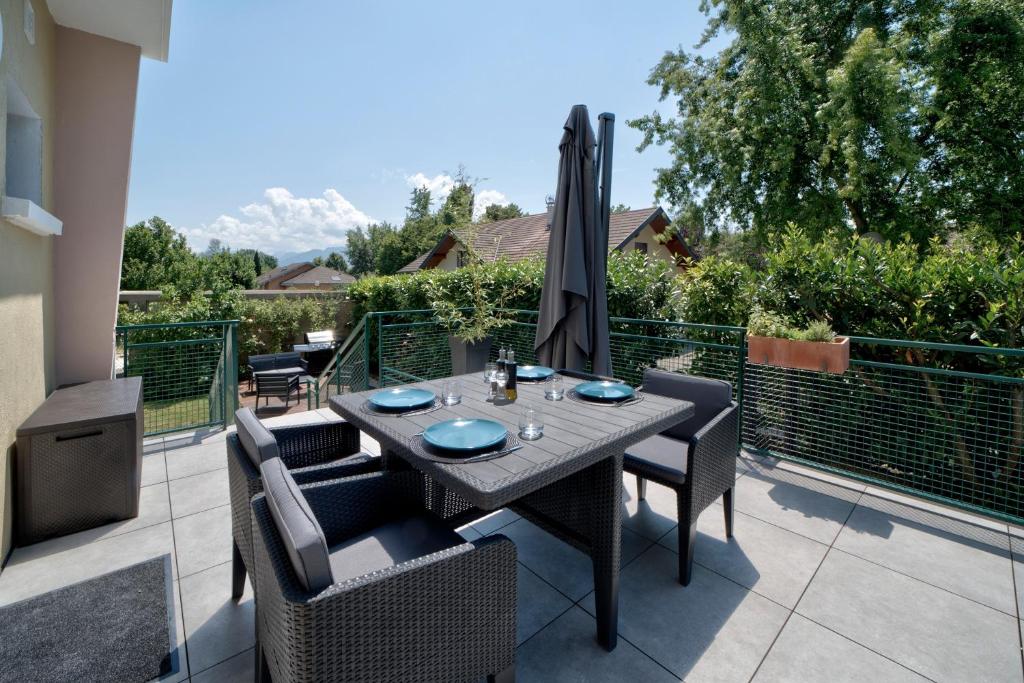 une table avec des chaises et un parasol sur une terrasse dans l'établissement Le Bach - Charmant Appt à 10min de Annecy, à Annecy