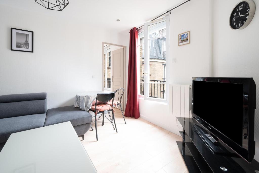un salon avec un canapé et une télévision dans l'établissement Le Moulinet - Appt dans le 13e Arr de Paris, à Paris