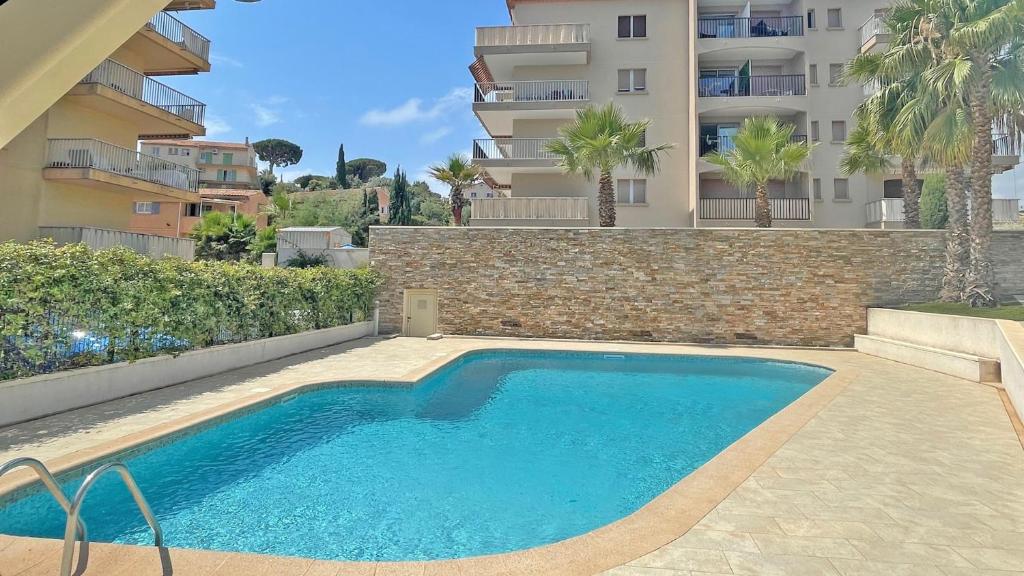 une piscine devant un immeuble dans l'établissement La Palmeraie, à Sainte-Maxime