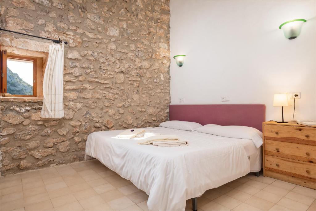 a bedroom with a bed and a stone wall at Petit Hotel Hostatgeria La Victoria in Alcudia