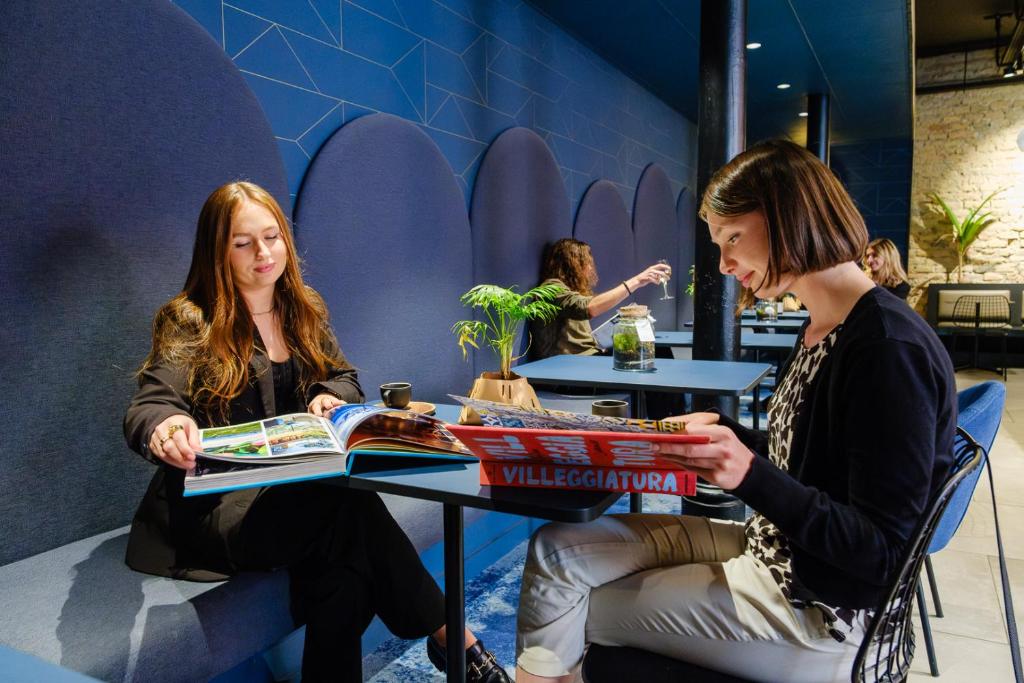 two women sitting at a table reading books at Hôtel Tandem - Boutique Hôtel in Strasbourg