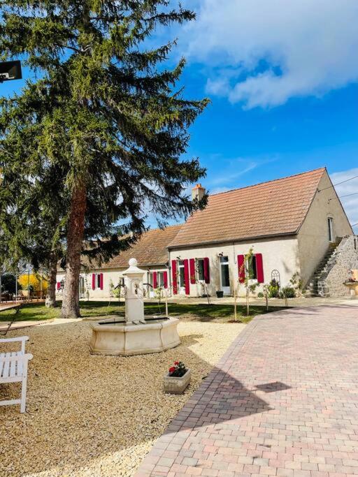 un bâtiment blanc avec un arbre et une fontaine dans l'établissement Le Family Pop-Art, à Montaigu-le-Blin