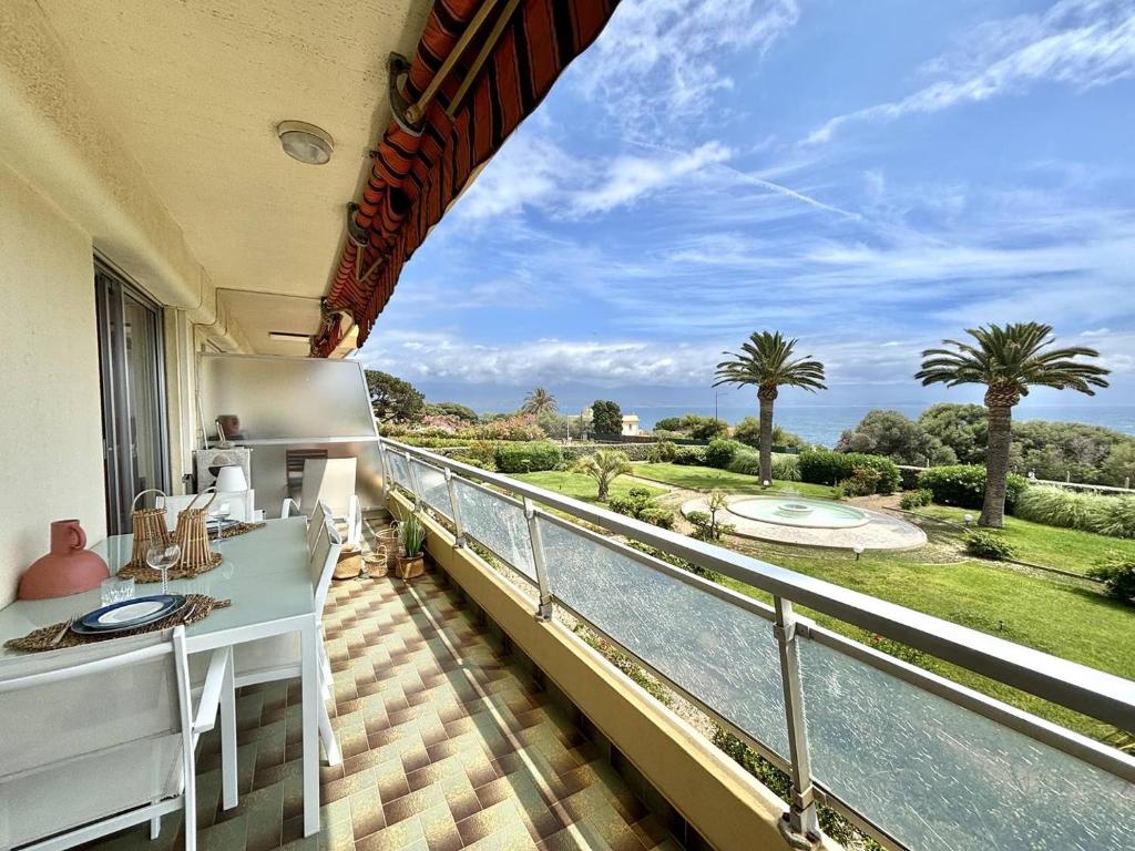 d'un balcon avec vue sur l'eau et les palmiers. dans l'établissement Appartement 2 pièces Le Versailles Ajaccio Sanguinaires, à Ajaccio
