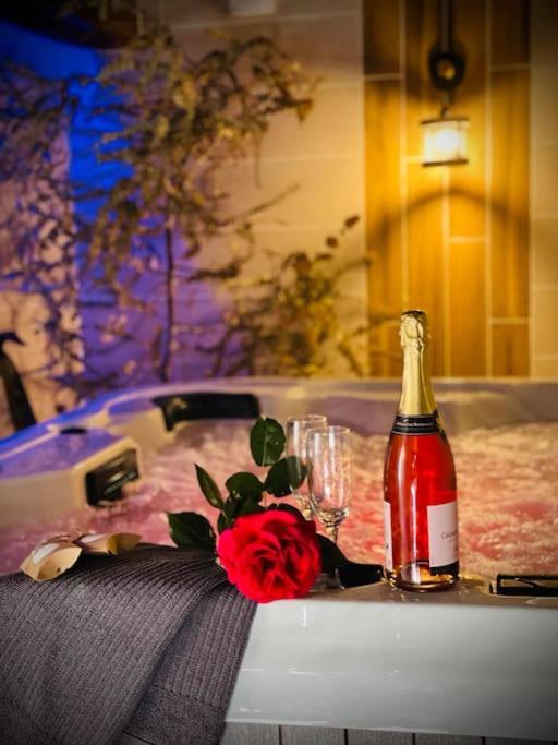 - une bouteille de champagne et une rose sur une table dans l'établissement Le chalet des bons vivants, à Montaigu-le-Blin