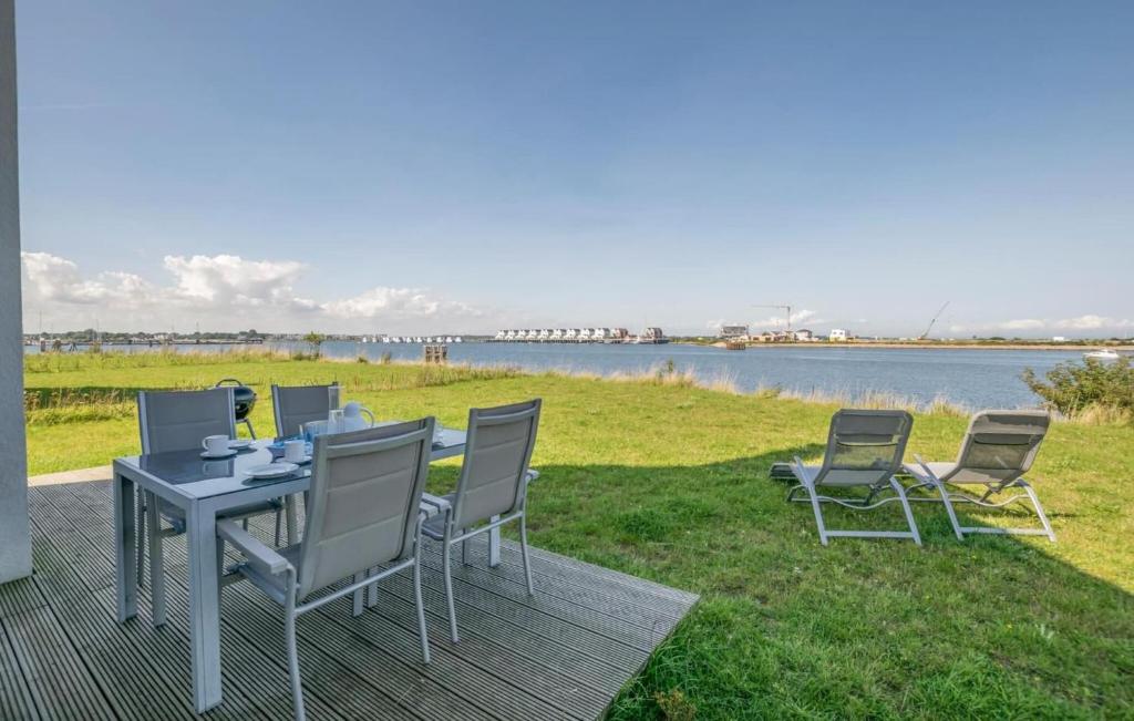 a table and chairs on a deck next to a body of water at Vogelvilla in Olpenitz