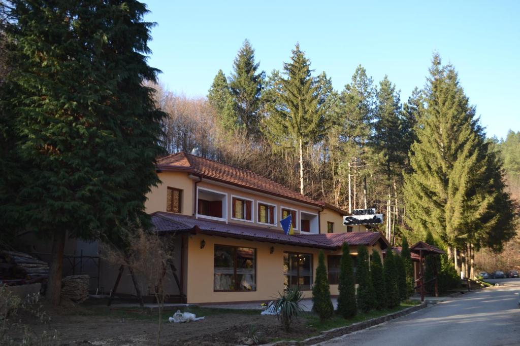 a house on the side of a road with trees at Motel Stovrela in Cazin