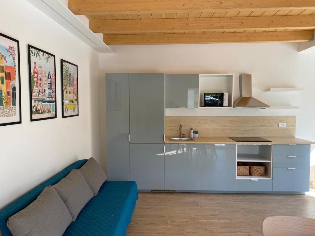 a living room with a blue couch and a kitchen at La casa nel verde in Recanati