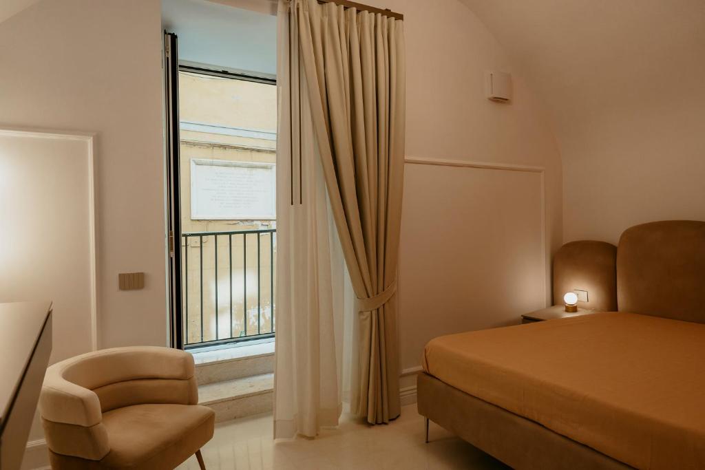 a bedroom with a bed and a chair and a window at Luxury apartment-Quartieri Spagn by Alux38 in Naples